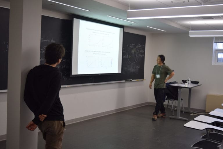 Two Man Standing on the Stage and Looking on the Screen in the Quantum Matter Workshop